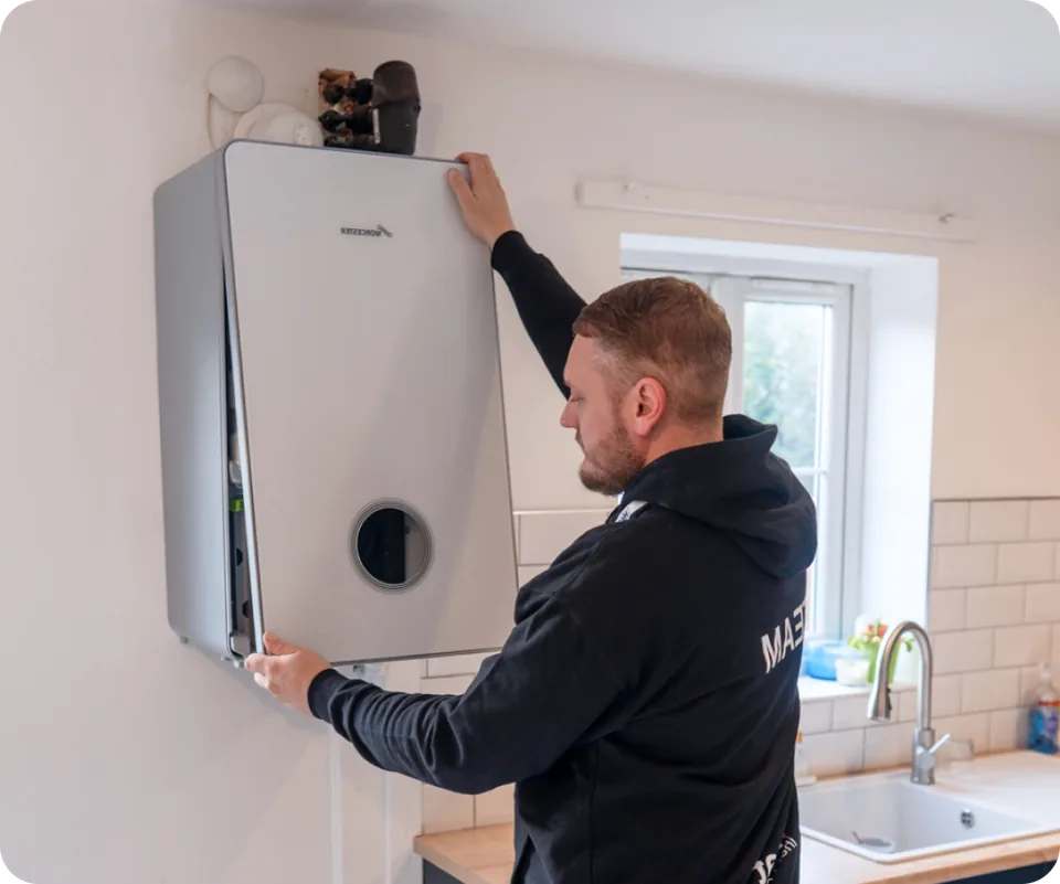 An engineer fitting the front cover of a Worcester Bosch boiler in a home