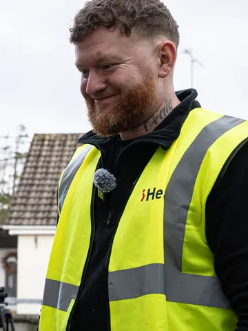 A smiling installer wearing an iHeat high-visibility vest