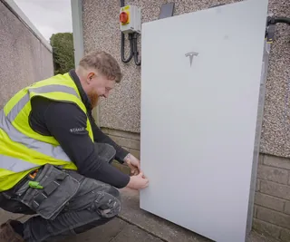 An iHeat installer working on a Tesla Powerwall home battery